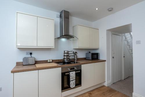 普里茅斯的住宿－Milton House，厨房配有白色橱柜和炉灶。