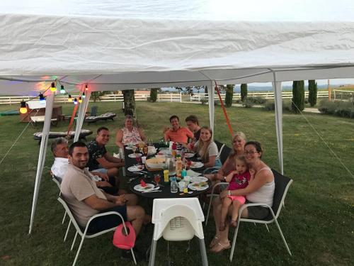 een groep mensen die aan een tafel onder een tent zitten bij Residence La Salamandre in Rabastens