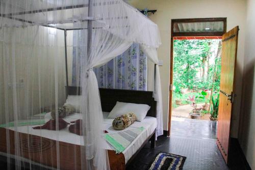 a bedroom with a canopy bed and a doorway at Manju Homestay in Sigiriya