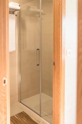 a shower with a glass door in a bathroom at Albergue "La Yalga" in Querúas