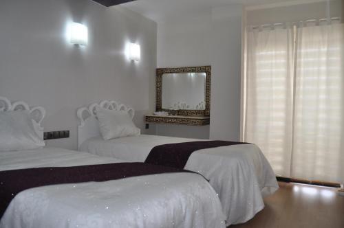 a white bedroom with two beds and a mirror at Garra Hotel in Konya