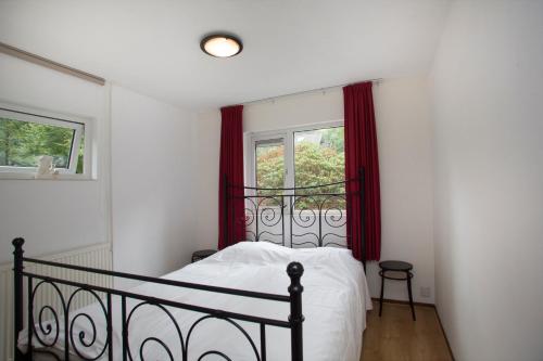 een slaapkamer met een bed en een raam met rode gordijnen bij 52 Horalaan in Bennekom