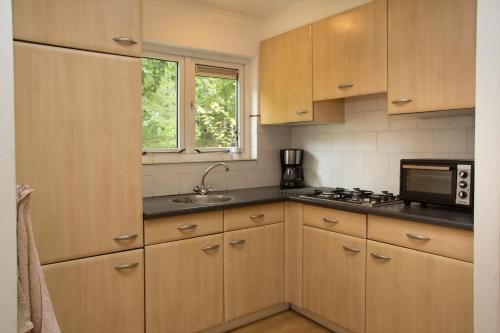 a kitchen with wooden cabinets and a microwave at 52 Horalaan in Bennekom