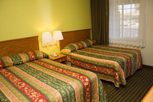 a hotel room with three beds with colorful blankets at King's Rest Motel in Gilroy