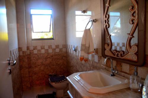 a bathroom with a sink and a mirror and a toilet at Pousada das Orquideas Foz in Foz do Iguaçu