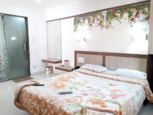 a bedroom with a bed with a floral bedspread at Hotel Sunrise in Mahabaleshwar
