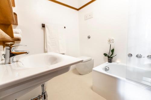 a white bathroom with a sink and a toilet at Dolomiti Sweet Lodge in Cortina dʼAmpezzo