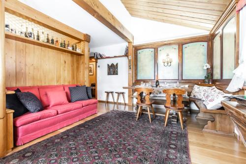 Una sala de estar con un sofá rojo y una mesa. en Dolomiti Sweet Lodge, en Cortina dʼAmpezzo