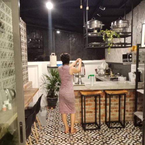 a woman standing in a kitchen drinking from a faucet at The Best Hotel in Bayan Lepas - THE LOV PENANG in Bayan Lepas