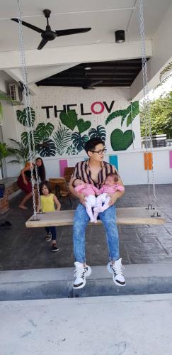 a man sitting on a swing holding a baby at The Best Hotel in Bayan Lepas - THE LOV PENANG in Bayan Lepas
