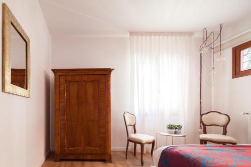 a bedroom with a bed and a dresser and two chairs at Laguna Boutique Apartments in Mestre