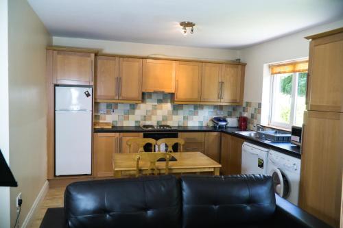 a kitchen with wooden cabinets and a black leather couch at Kerry-Lee Holiday Homes Tralee in Tralee
