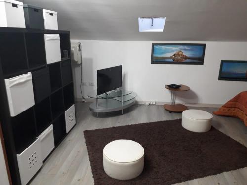 a living room with two white stools and a television at Tigli Carraro in San Cataldo