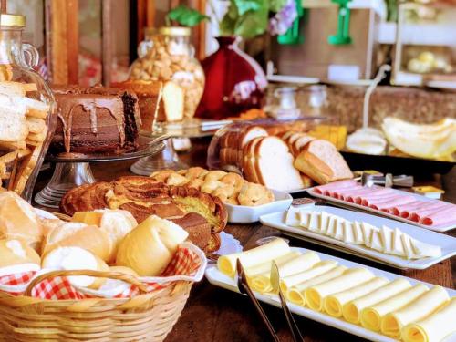 Una mesa con varios pasteles y panes sobre en Pousada Papaya Container, en Ubatuba
