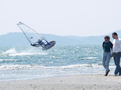 a man and woman walking on the beach with a sail boat at Koronisia Apartments in Koronisia