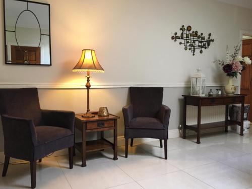 una sala de espera con 2 sillas y una lámpara en Abbeyvilla Guesthouse Room Only en Adare
