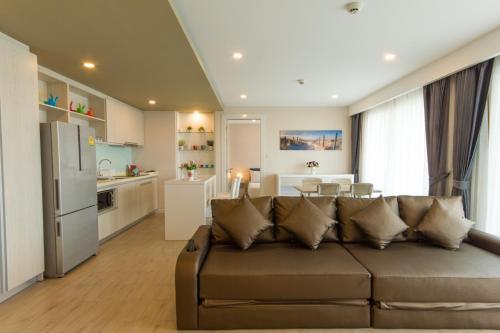 a living room with a brown couch and a kitchen at Seven Seas Condo Resort by Jay Jay in Jomtien Beach