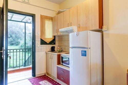 a kitchen with a white refrigerator and a balcony at Koronisia Apartments in Koronisia