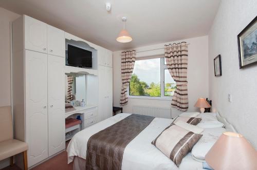 a white bedroom with a bed and a window at The Waterfront House Country Home in Oughterard
