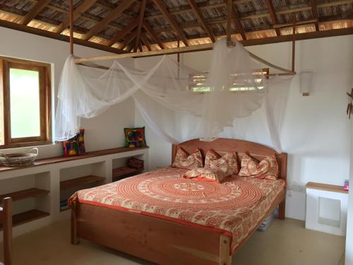 a bedroom with a bed with a mosquito net at Sunshine Cafe in Tangalle