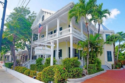 a white house with palm trees in front of it at La Pensione Inn - Adult Exclusive in Key West
