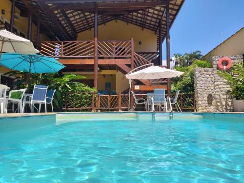 einen Pool mit Stühlen und Sonnenschirmen in der Unterkunft Pousada Maui in Ubatuba