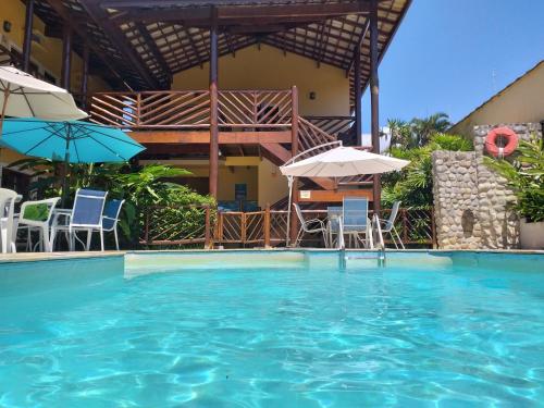 a swimming pool with chairs and umbrellas at Pousada Maui in Ubatuba
