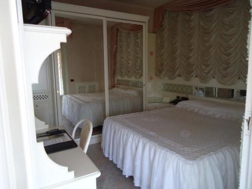 a white bedroom with two beds and a mirror at Hotel Matilde in Marina di Massa