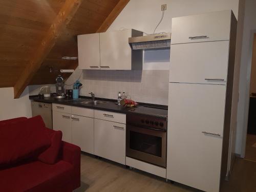 a kitchen with white appliances and a red couch at Ruhige Wohnung bei München, Fürstenfeldbruck, Dachau in Oberschweinbach