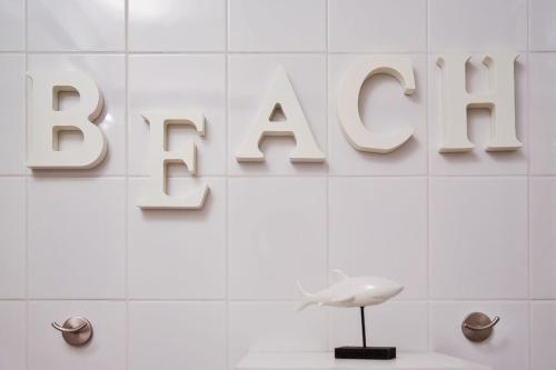 a white tiled wall with the sign for a bathroom at Willa 4 Pory Roku & Uznam in Świnoujście