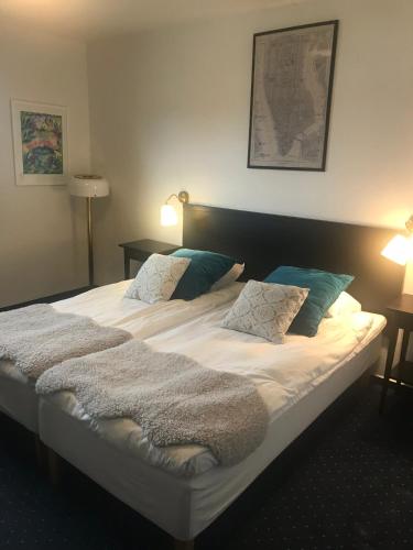a large bed with white sheets and blue pillows at Rasta Lilla Edet in Lilla Edet