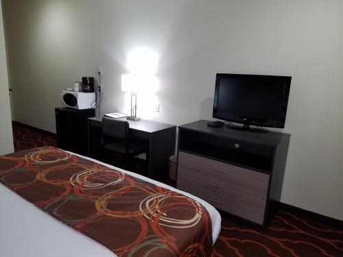 a hotel room with a bed and a flat screen tv at Baymont by Wyndham Grovetown Augusta in Augusta