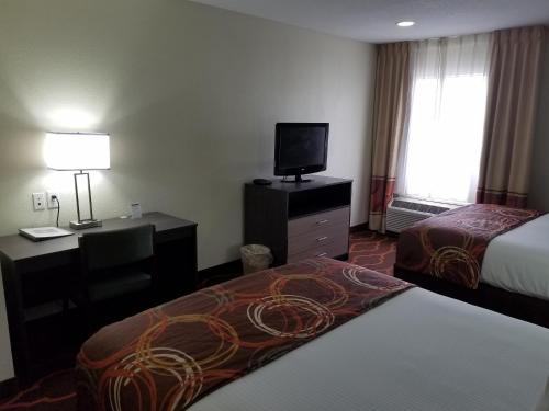 a hotel room with two beds and a flat screen tv at Baymont by Wyndham Grovetown Augusta in Augusta