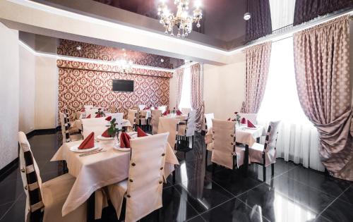 a restaurant with white tables and chairs and a chandelier at Sergeev Hotel in Mykolaiv