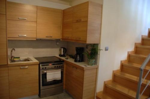uma cozinha com armários de madeira e um forno com placa de fogão em Thalia Rooms em Kalabaka
