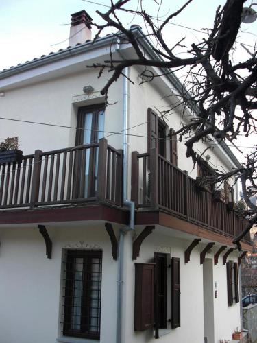 a white building with a balcony on the side of it at Thalia Rooms in Kalabaka