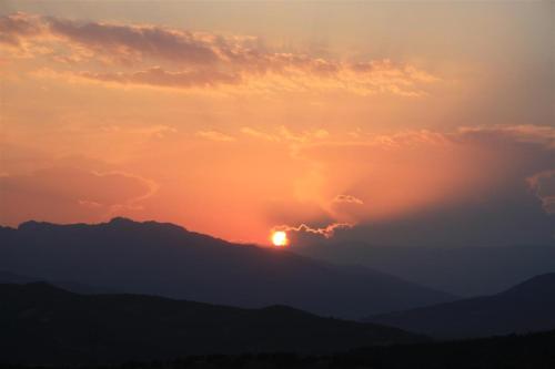 a sunset over a mountain with the sun in the clouds at Thalia Rooms in Kalabaka