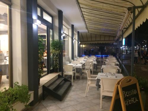 um restaurante com mesas brancas e cadeiras brancas em Hotel Portofino em Caorle