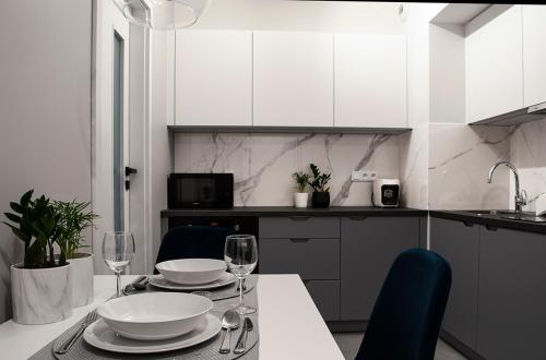 een keuken met een tafel met borden en wijnglazen bij NavyBlue apartment Cracow free parking TV in Krakau