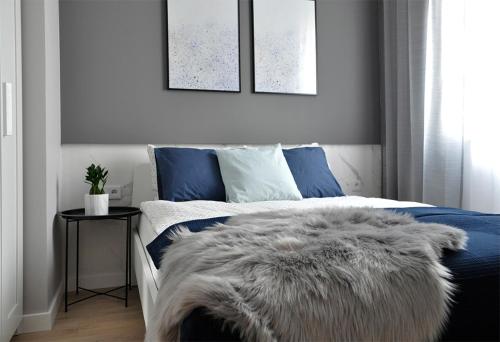 een slaapkamer met een blauw en wit bed en een harige deken bij NavyBlue apartment Cracow free parking TV in Krakau