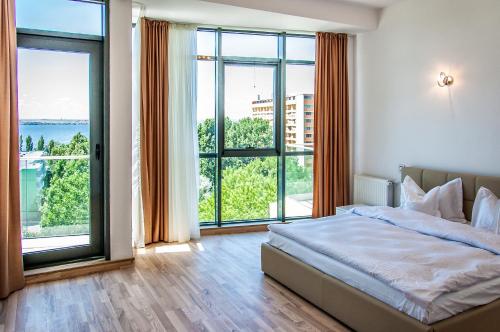 a bedroom with a bed and large windows at Riviera Residence Apartments in Mamaia