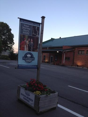 a sign on the side of a street with flowers at West Gate Bed and Breakfast in Gananoque