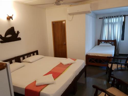 1 dormitorio con 2 camas, mesa y sillas en Thiranagama Beach Hotel, en Hikkaduwa