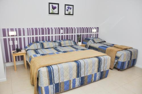 Un dormitorio con 2 camas y una mesa con una falda. en BR Suítes Hotel, en Navegantes