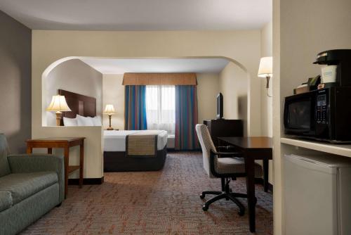 ベルビルにあるBaymont by Wyndham Belleville Airport Area Free Airport Shuttleのベッドと机があるホテルの部屋