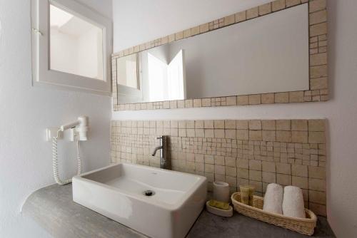 uma casa de banho com um lavatório branco e um espelho. em Gorgona Villas em Imerovigli