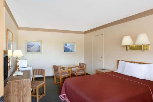 a hotel room with a bed and a table and chairs at Howard Johnson by Wyndham Brigham City in Brigham City