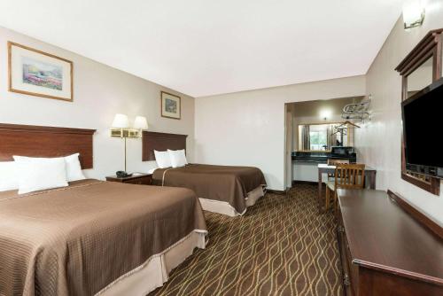 a hotel room with two beds and a flat screen tv at Howard Johnson by Wyndham Springfield in Springfield