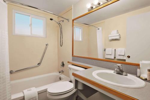 a bathroom with a sink and a toilet and a mirror at Travelodge by Wyndham Quesnel BC in Quesnel