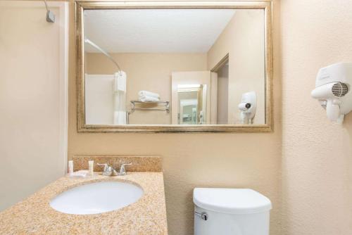 a bathroom with a sink and a mirror and a toilet at Howard Johnson by Wyndham Historic Lake Charles in Lake Charles